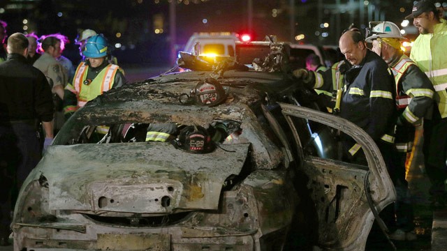 Firefighters around burned limousine with 4 bodies inside